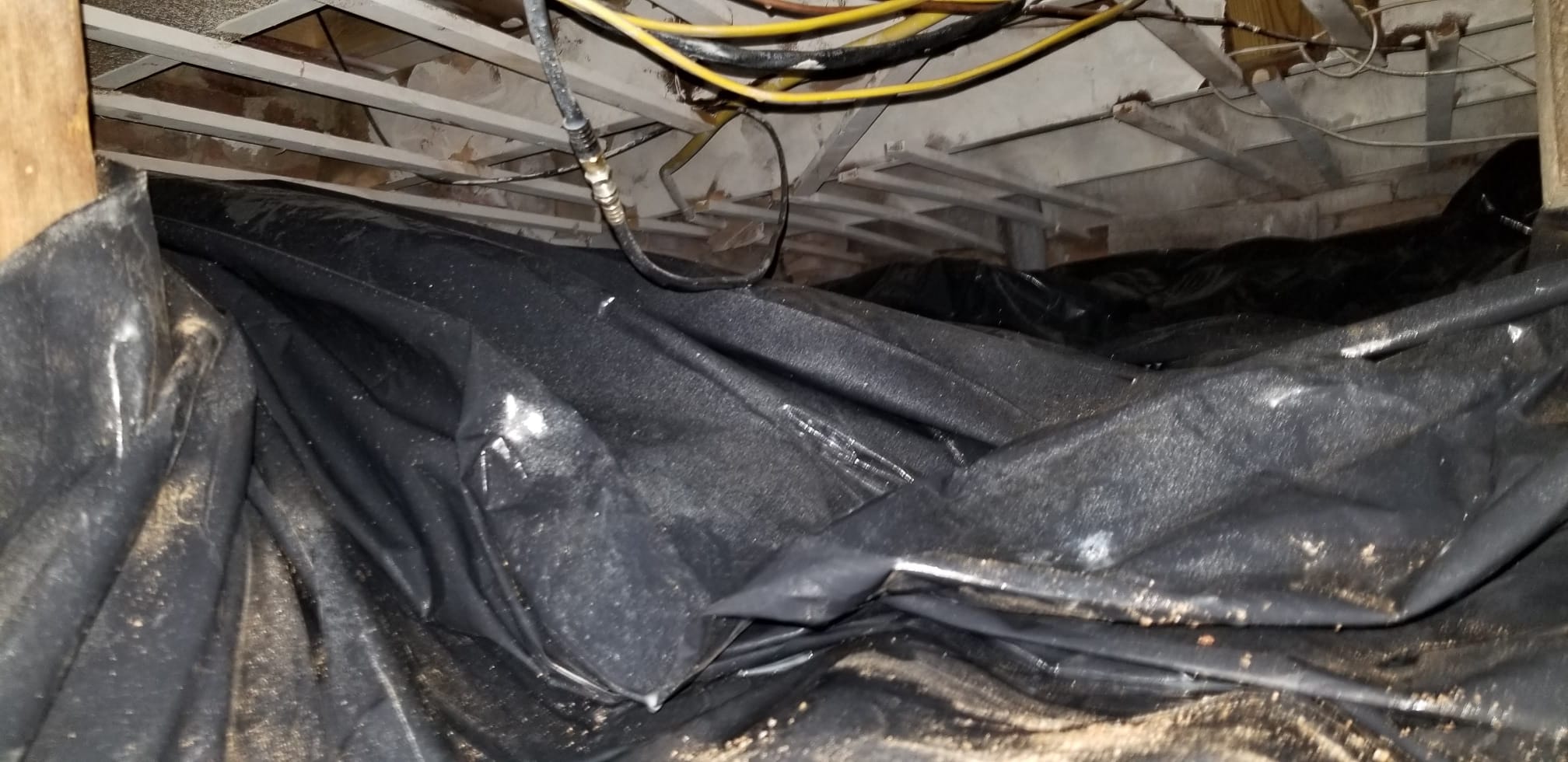 Old damaged vapor barrier in a crawl space