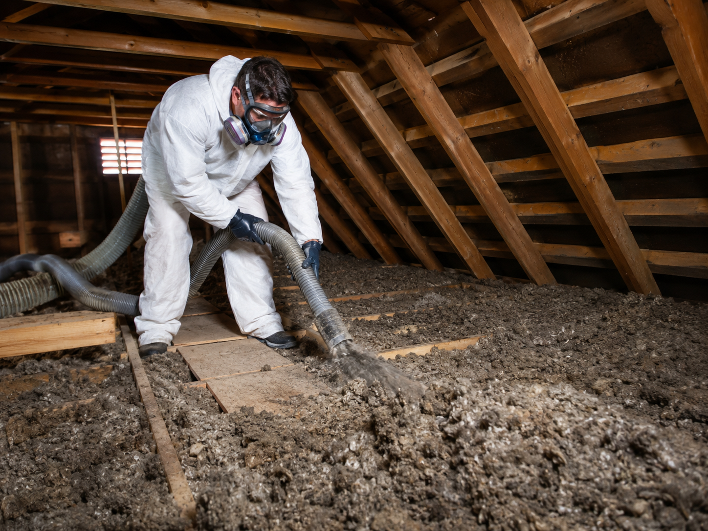 Technician vacuuming old and deteriorated attic insulation in an Annapolis, Maryland home