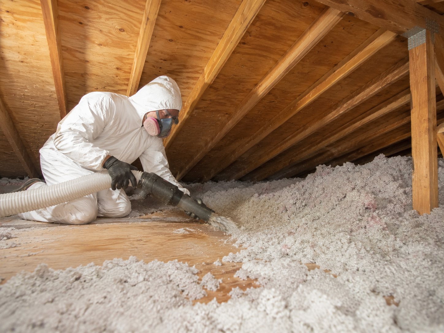 Technician wearing protective equipment while vacuuming old blown-in insulation from an attic in Severna Park, Maryland